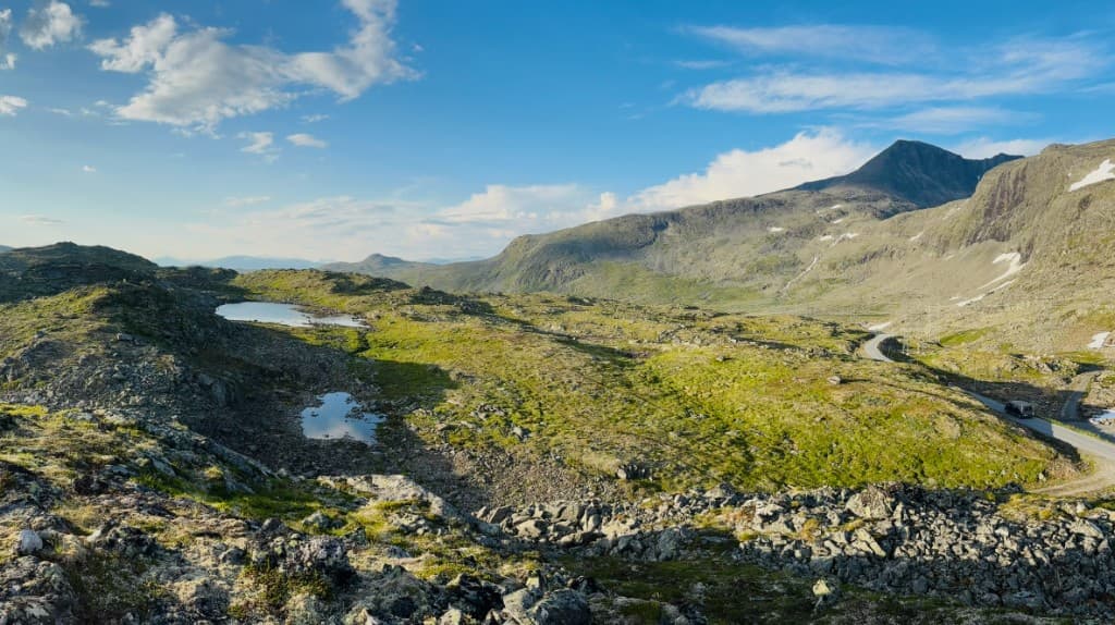 Rocky highland with small lakes and a road winding past a mountain